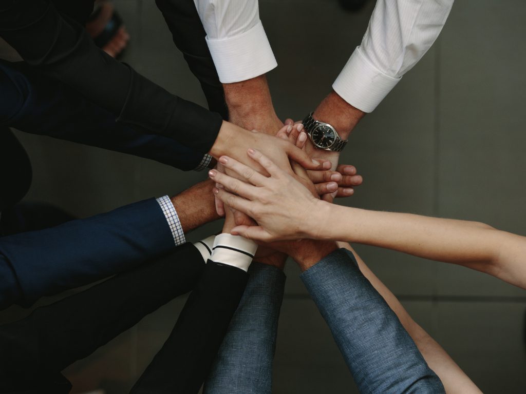 Pessoas unindo as maos em compromisso coletivo